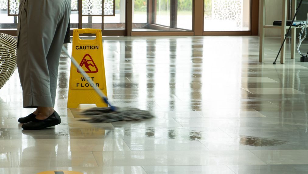 濡れたタイル床と注意喚起サインが設置された清掃中のフロアの様子